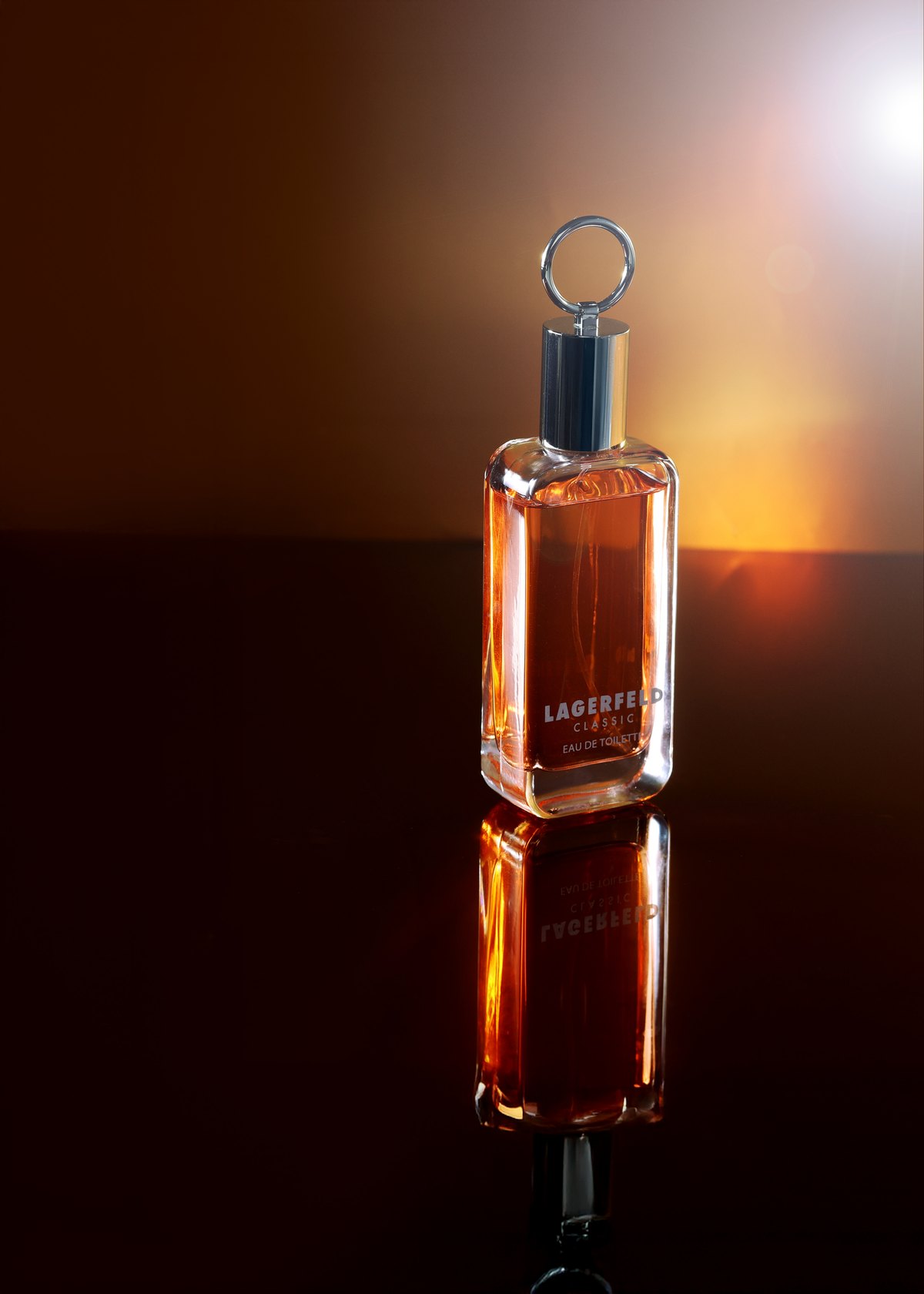 Parfumflakon steht im Gegenlicht vor einem orangeroten Farbverlauf