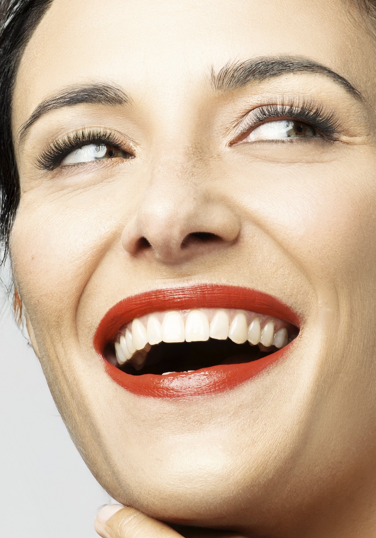 Beautyportrait einer lachenden Frau mit kräftig rotem Lippenstift