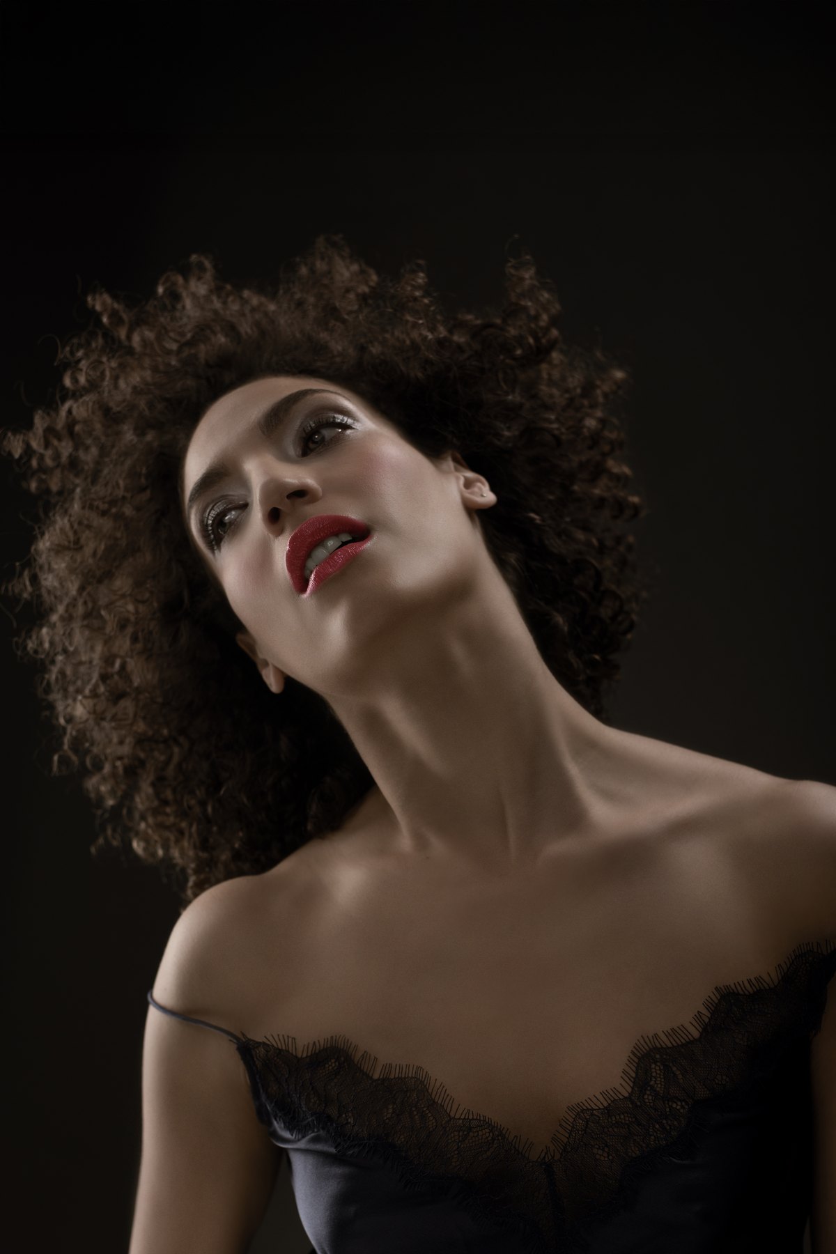 Low-Key-Portrait einer Frau mit Locken in schwarzer Spitze
