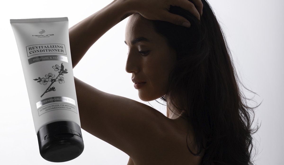 Frau im Profil mit erhobenem Arm, davor eine helle Revitalizing Conditioner Tube