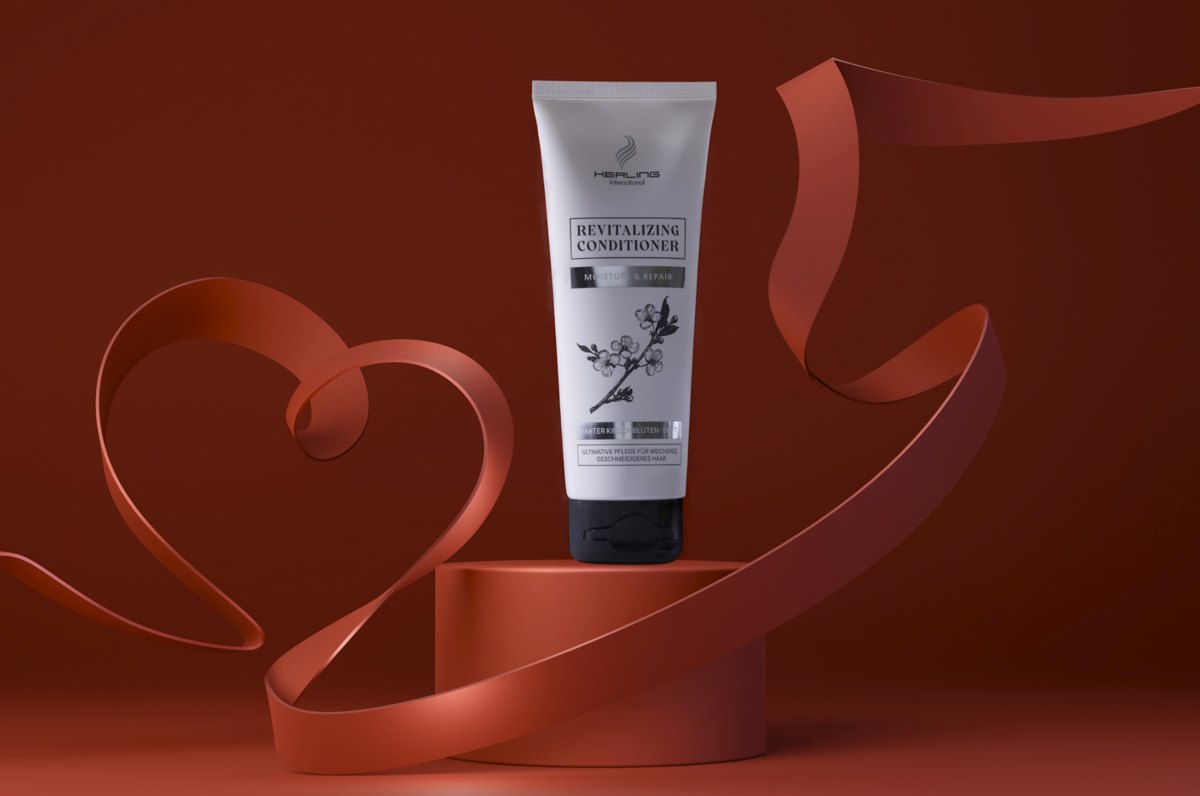 Helle Revitalizing Conditioner Tube auf einem Podest, umspielt von einem herzförmigen Band vor rotbraunem Hintergrund