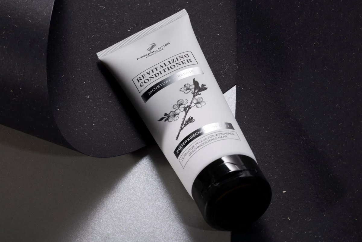Helle Revitalizing Conditioner Tube liegt zwischen schwarzem und silbernem Papier
