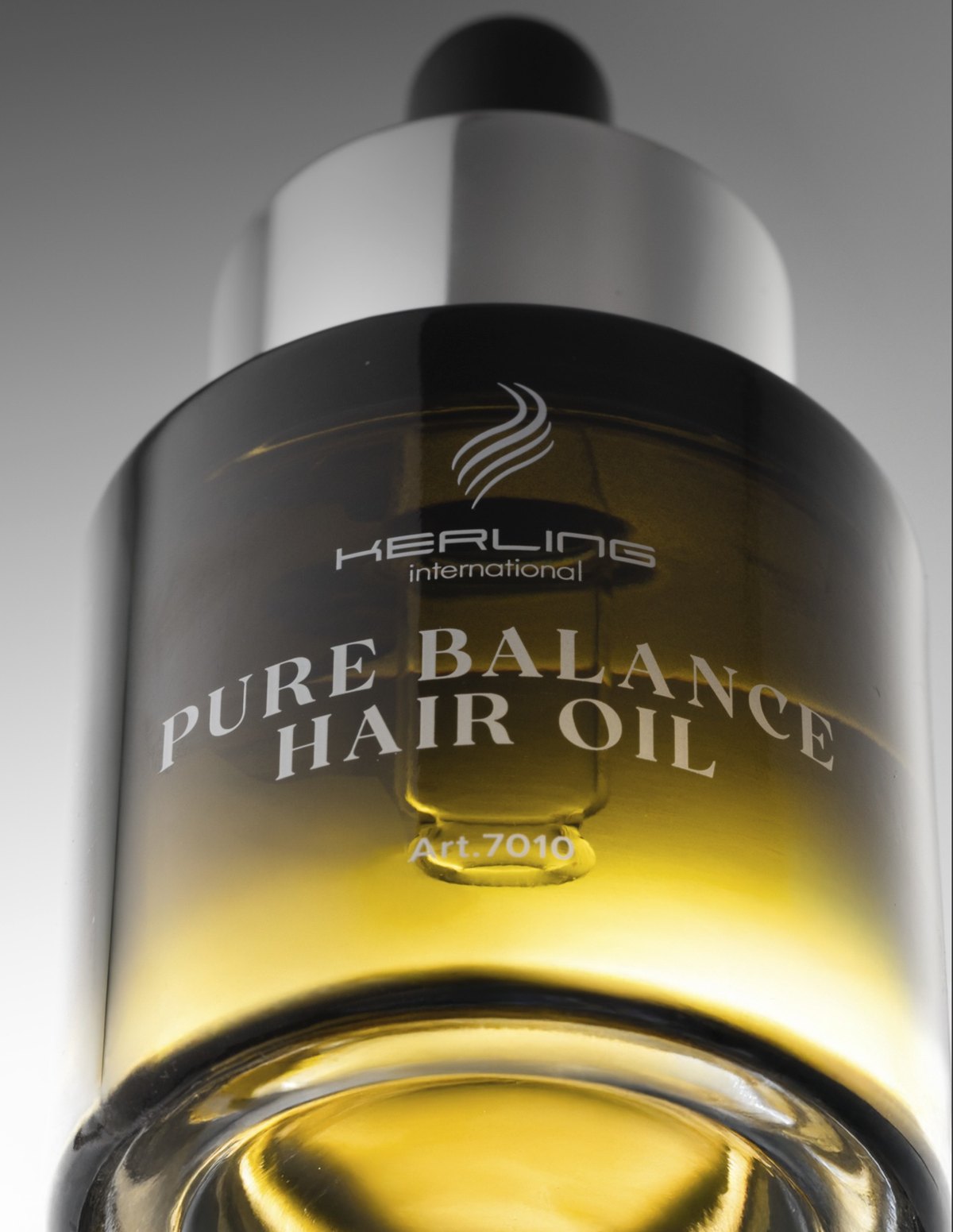 Makro einer Kerling Pure Balance Hair Oil Flasche mit goldenem Öl und silbernem Deckel vor grauem Verlauf