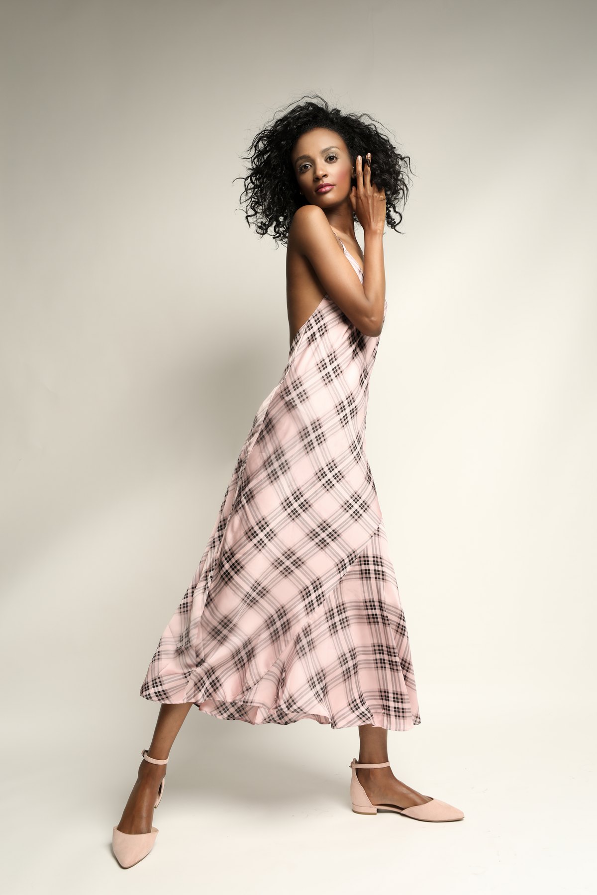 Model im karierten Sommerkleid in Bewegung vor hellem Hintergrund
