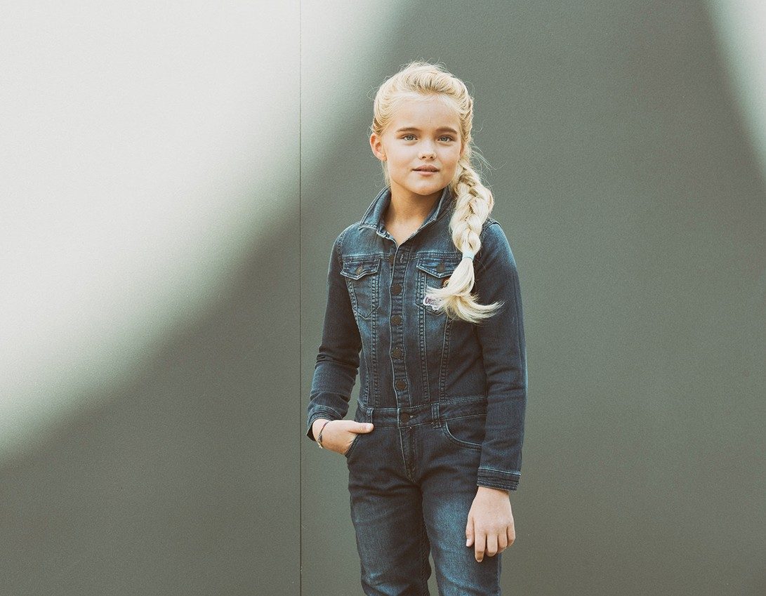 Mädchen im Denim-Outfit vor grauer Wand im weichen Tageslicht