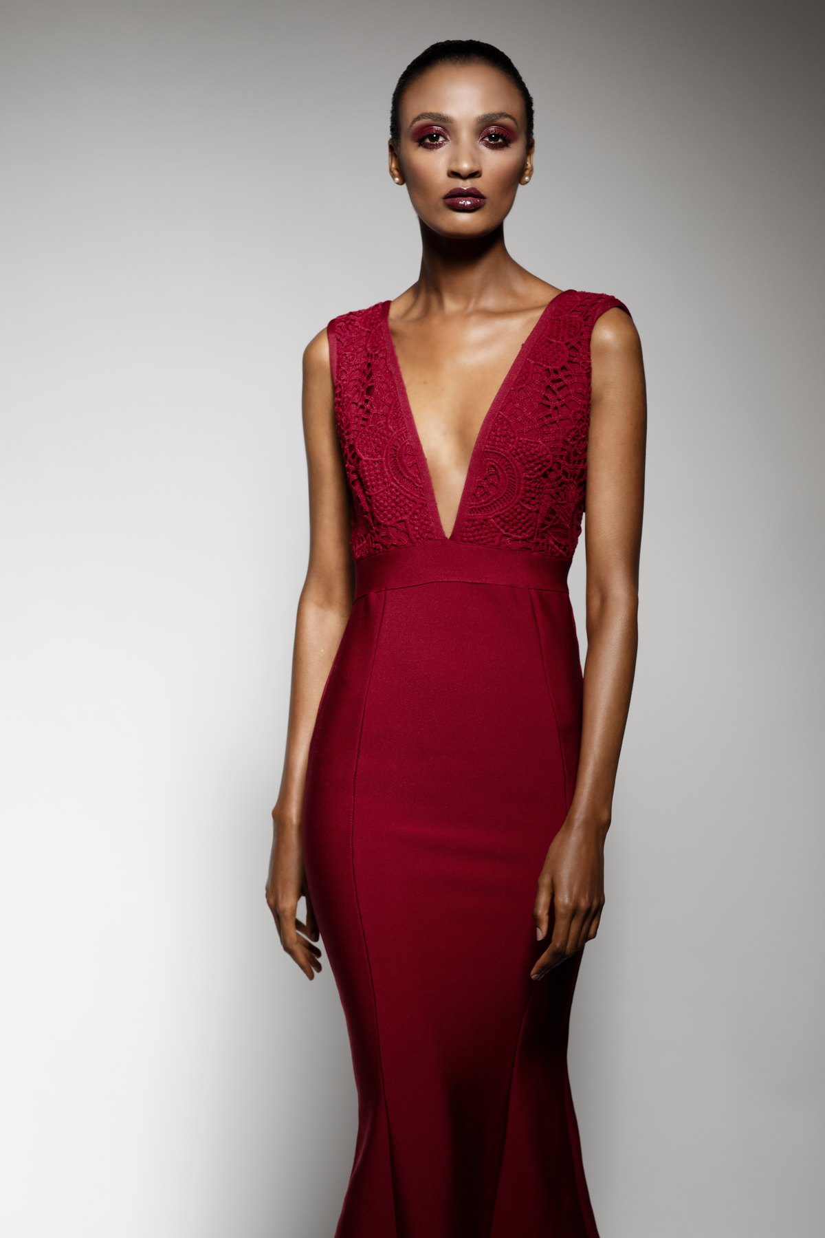 Model im roten Abendkleid mit tiefem Ausschnitt vor heller Wand