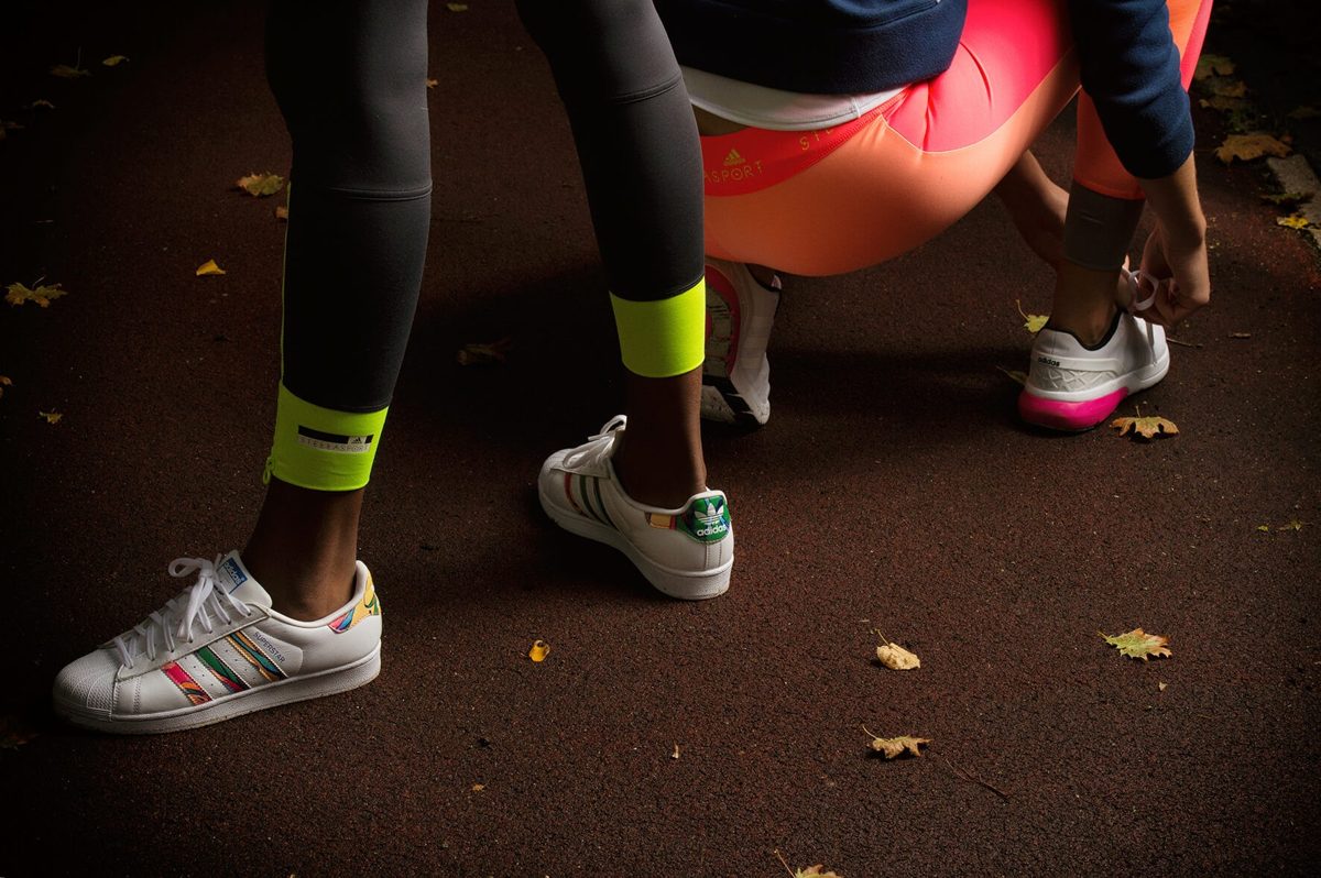 Detailaufnahme weißer Sneaker und Sportleggings auf herbstlichem Asphalt