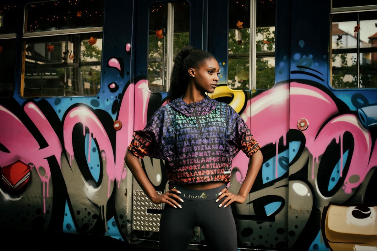 Junge Frau in Sportmode posiert vor einer Graffitiwand