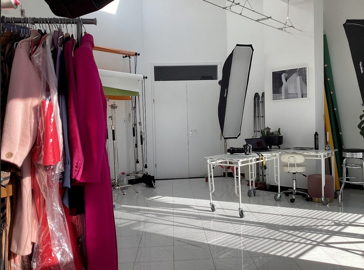 Fotostudio mit Kleiderstange voller Mäntel und Lichtaufbau für ein Modeshooting