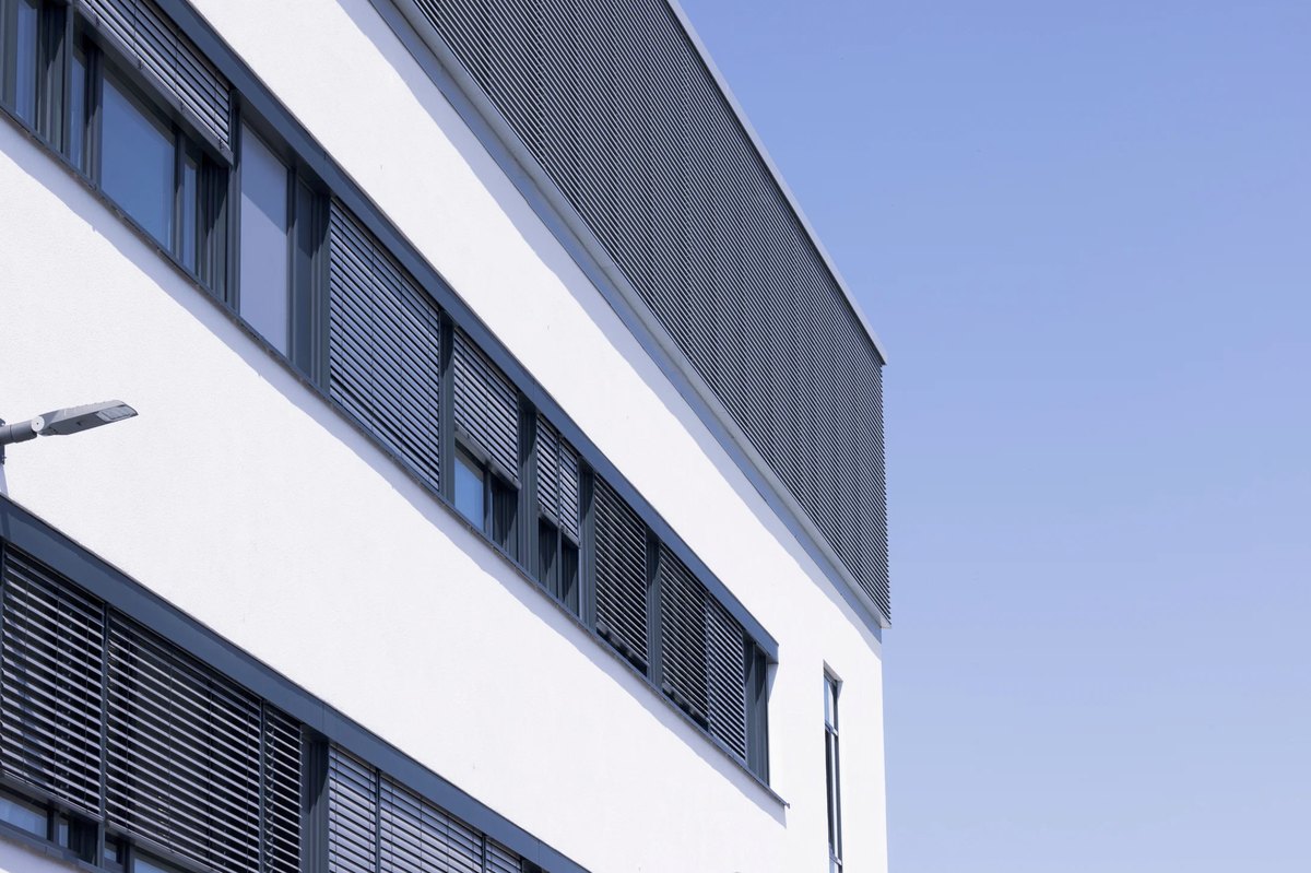 Moderne Bürofassade mit umlaufendem Fensterband und weißer Attika