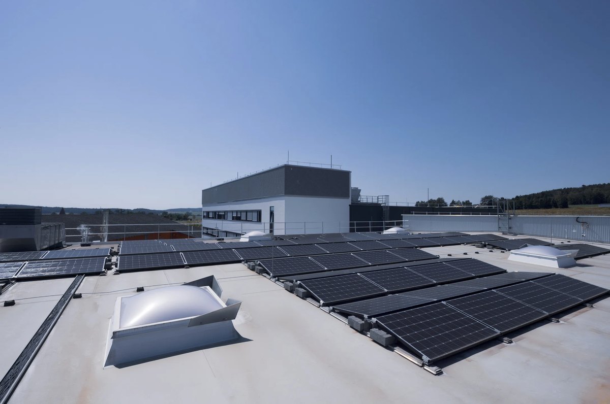 Flachdach mit Photovoltaikreihen und Oberlichtern über einem Gewerbebau