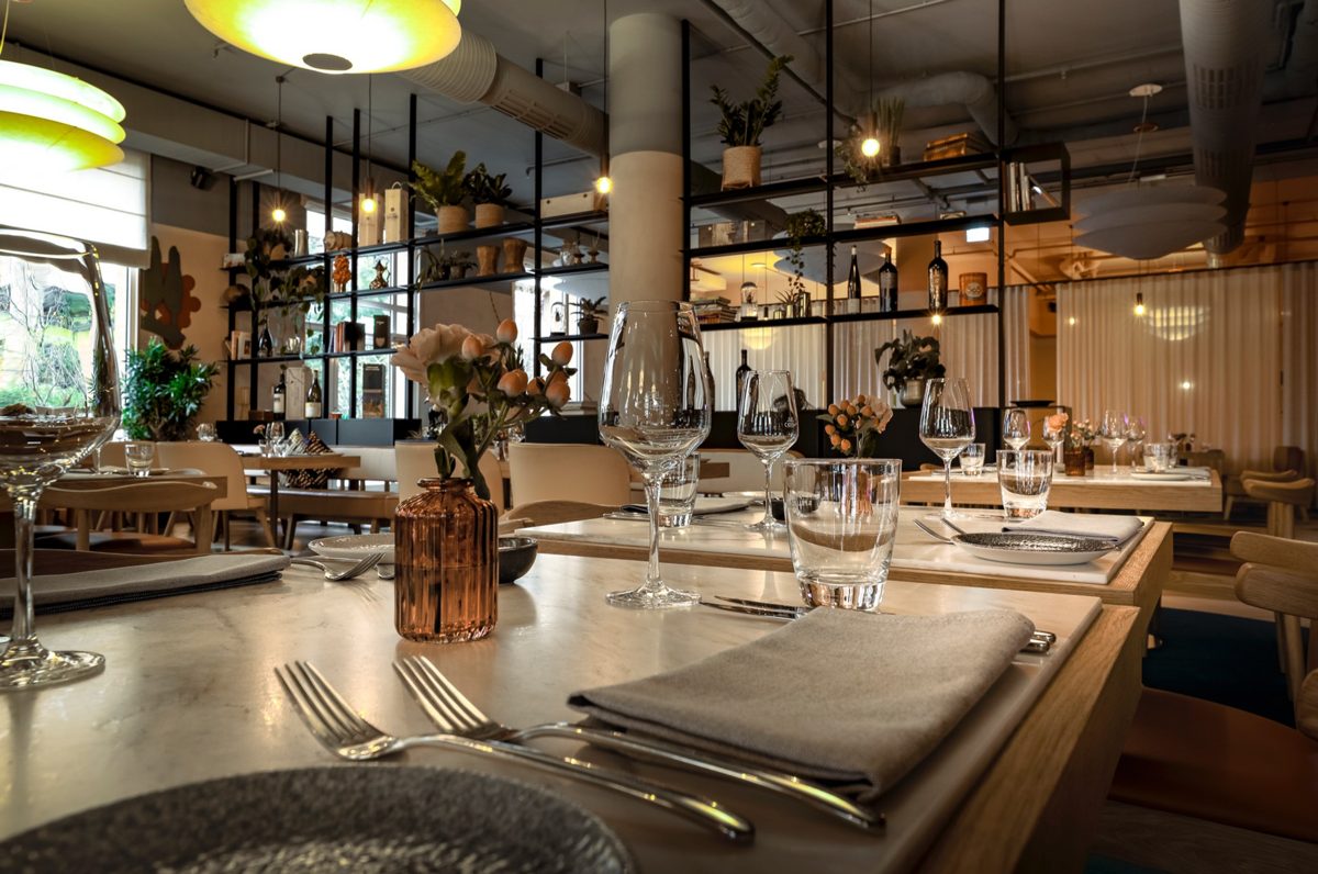 Detail eines eingedeckten Restauranttisches mit Gläsern, Besteck und Blumenvase