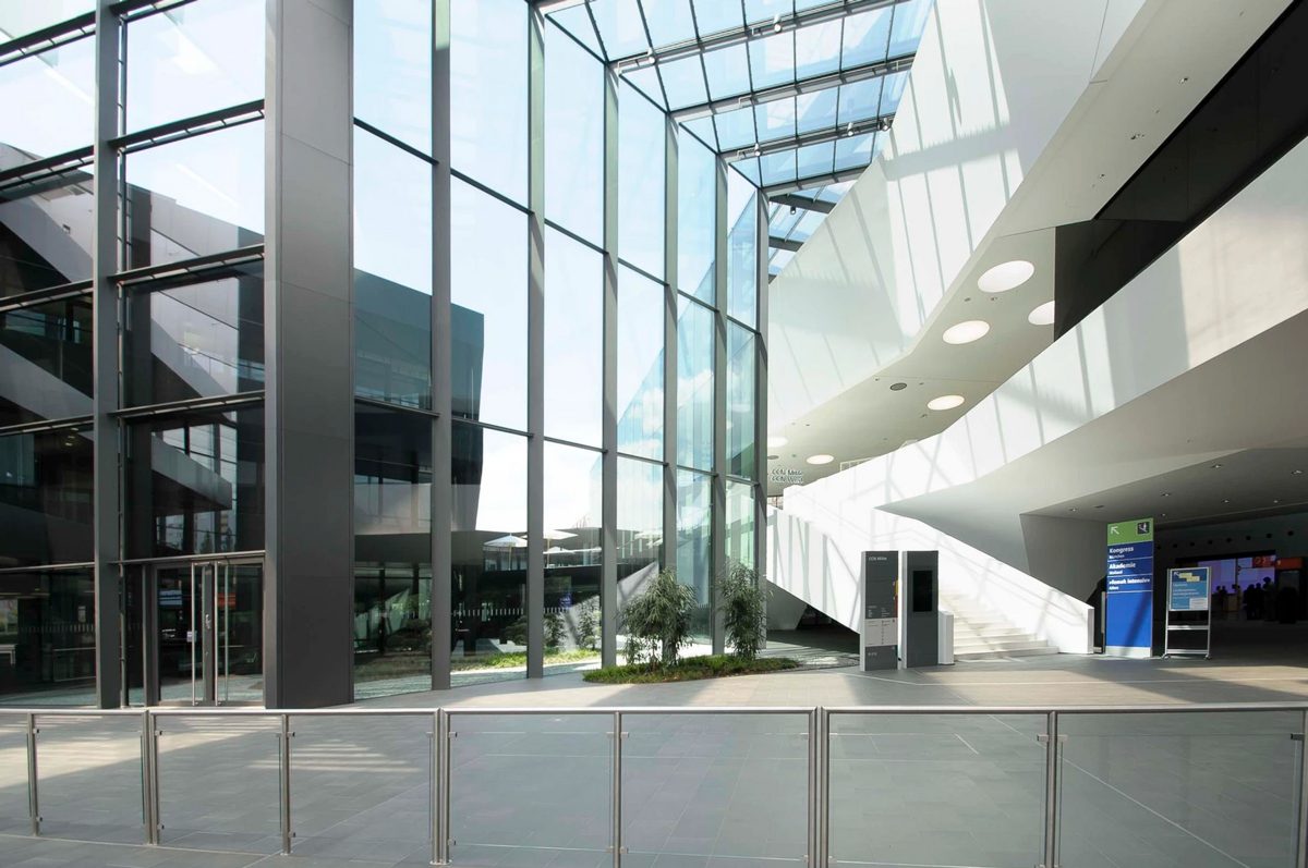 Foyer mit hoher Glasfassade und geschwungener Lichtdecke mit Blick nach draussen