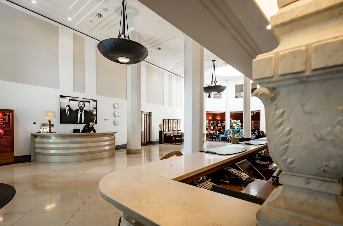 Empfangsbereich mit geschwungener Rezeptionstheke und Pendelleuchten in heller Lobby
