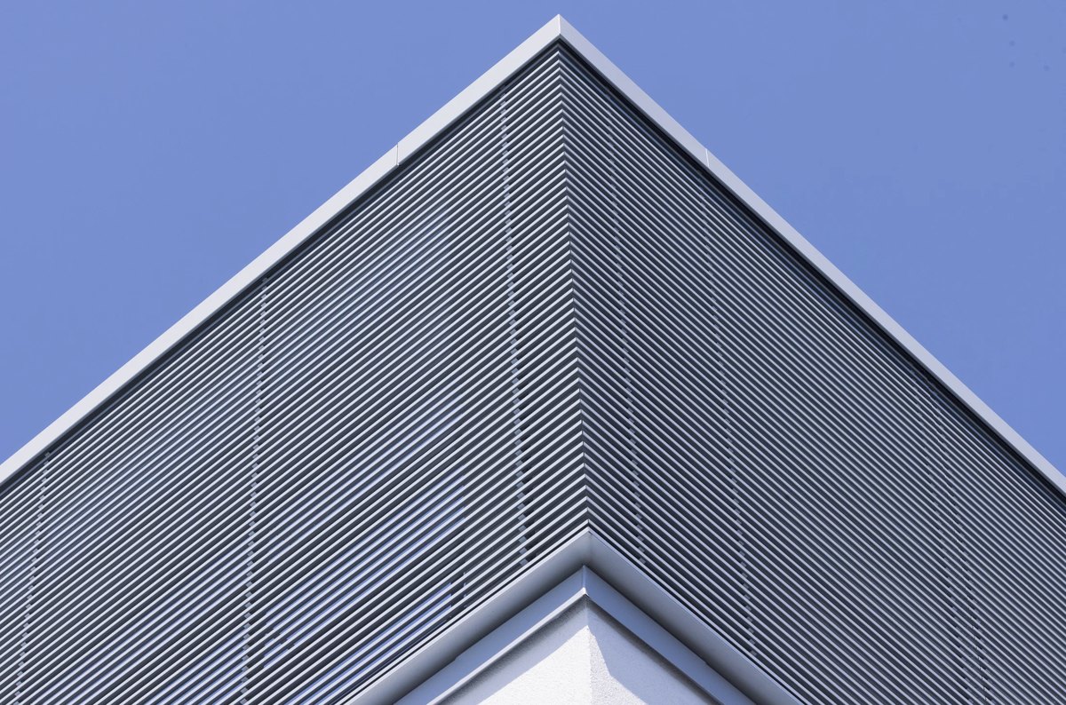 Giebel eines Neubaus mit horizontaler Lamellenfassade vor blauem Himmel