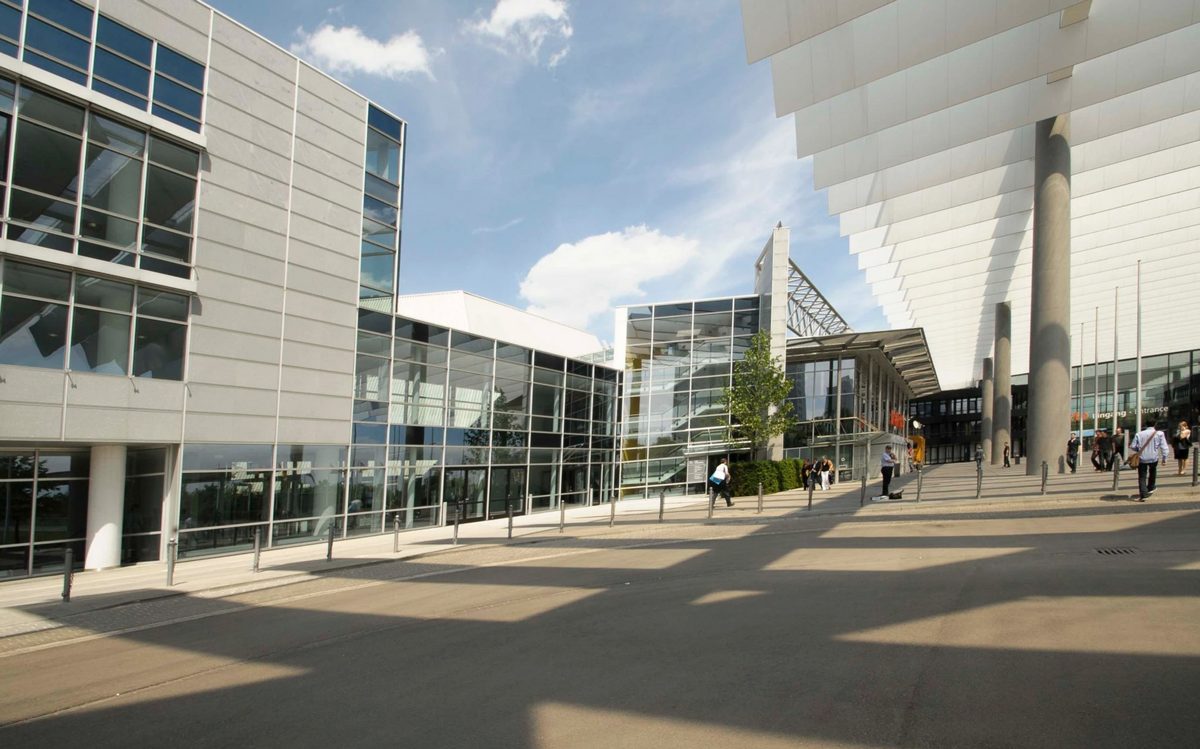 Moderne Messegebäude mit Glasfassade und weißem Vordach unter blauem Himmel