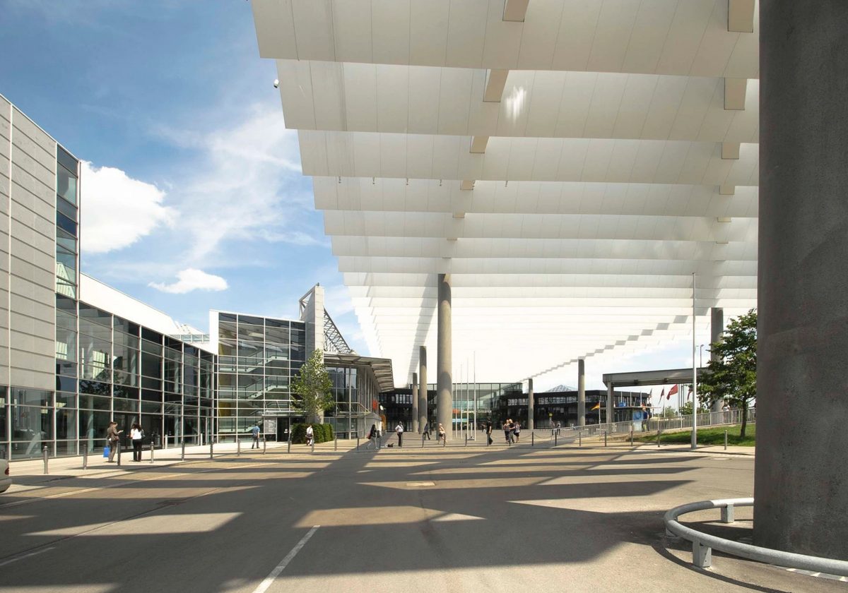 Überdachte Messepromenade mit weißen Dachlamellen und Glasfassade in Fluchtperspektive