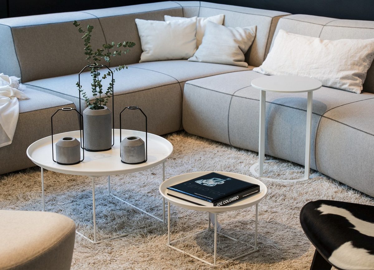 Graues Modulsofa mit runden Beistelltischen und Hochflorteppich in heller Wohnlounge