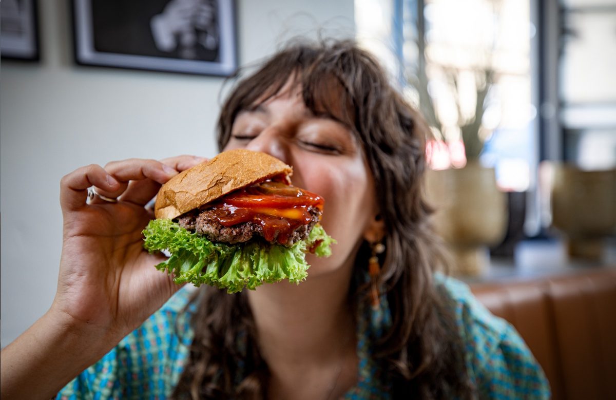 Frau beisst genussvoll in einen Burger in einem Restaurant