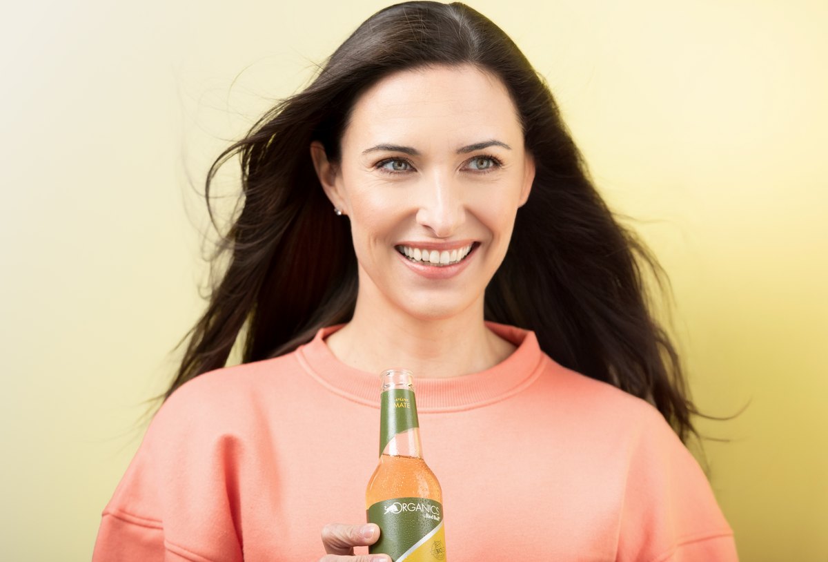 Frau mit Limonadenflasche vor cremefarbenem Hintergrund