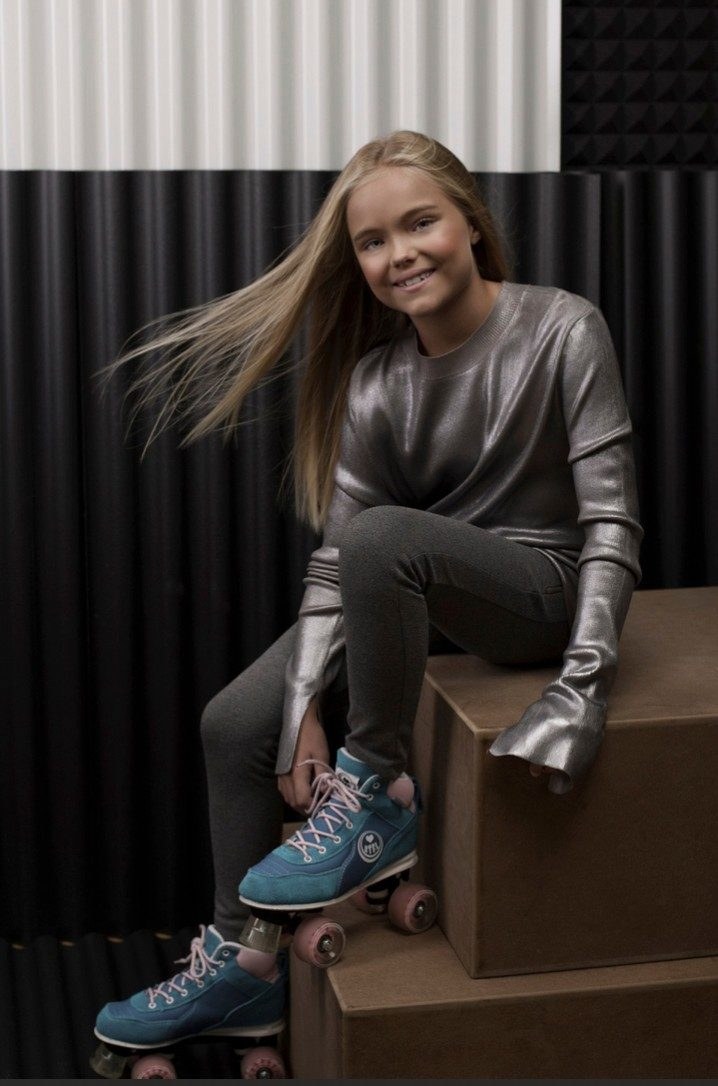 Mädchen mit Rollschuhen und silbrigem Oberteil vor grafischer Studiokulisse