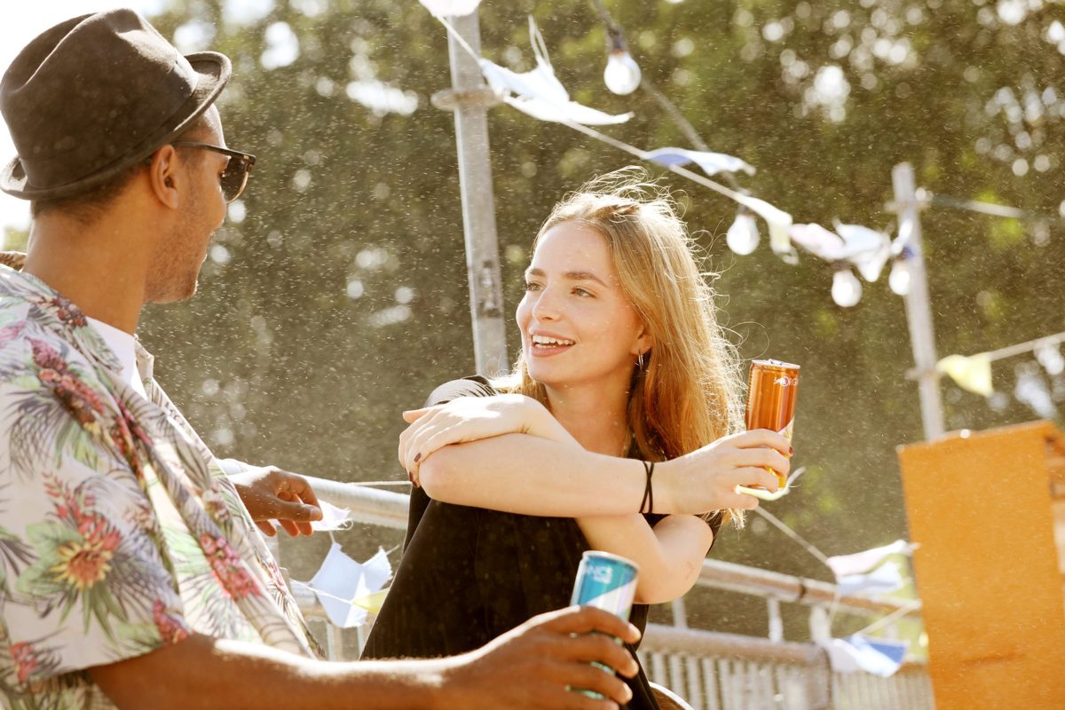 Zwei Menschen mit Getränkedosen im Gegenlicht auf einem Sommerfest