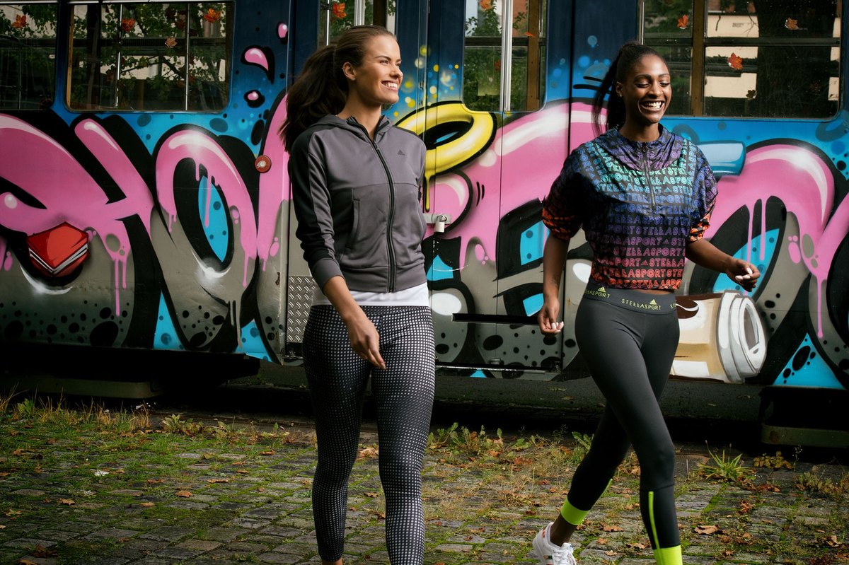 Zwei laufende Frauen in Sportkleidung vor einer graffitibesprühten Strassenbahn
