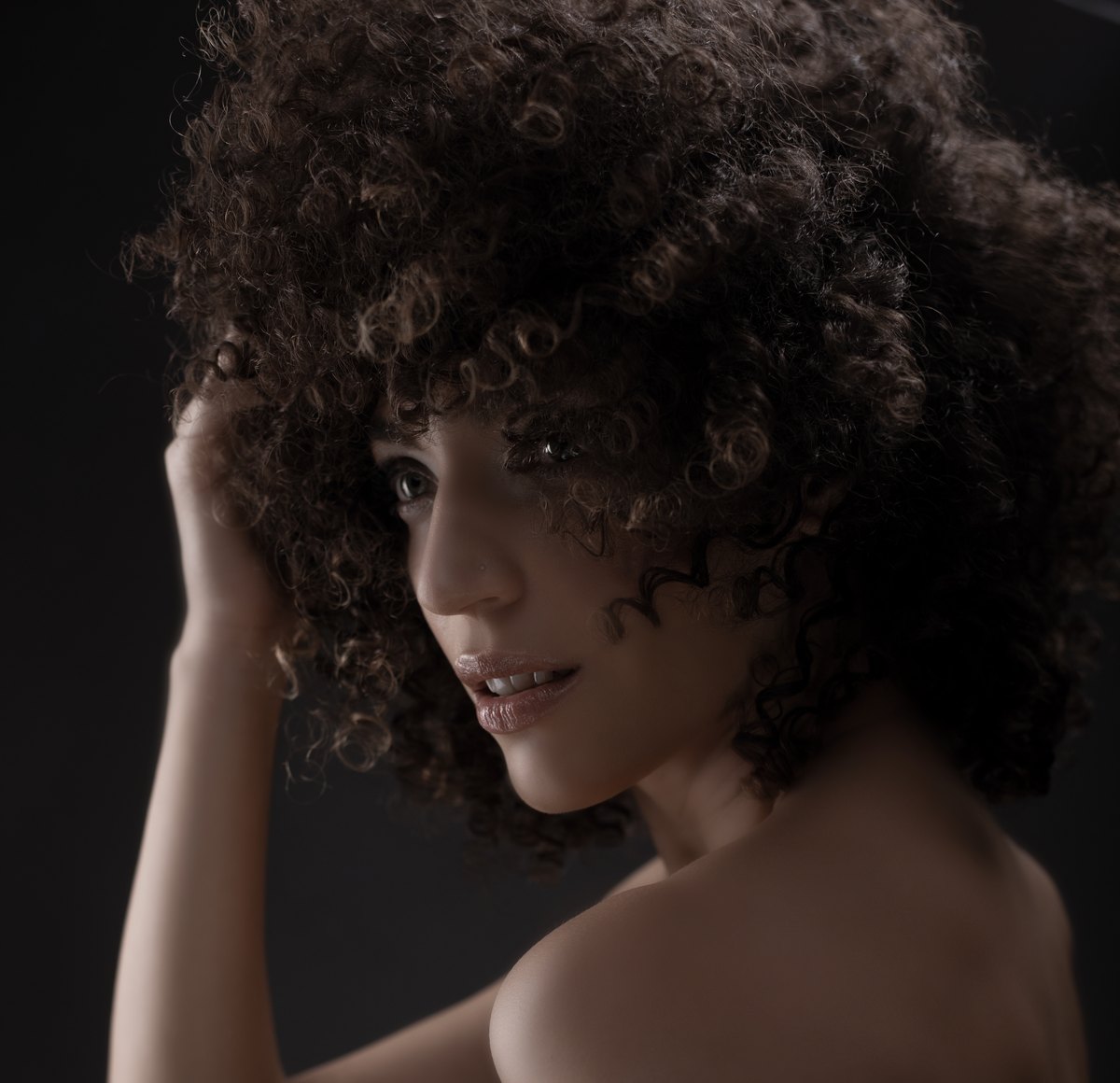 Frau mit voluminösen Afrolocken im Schulterblick