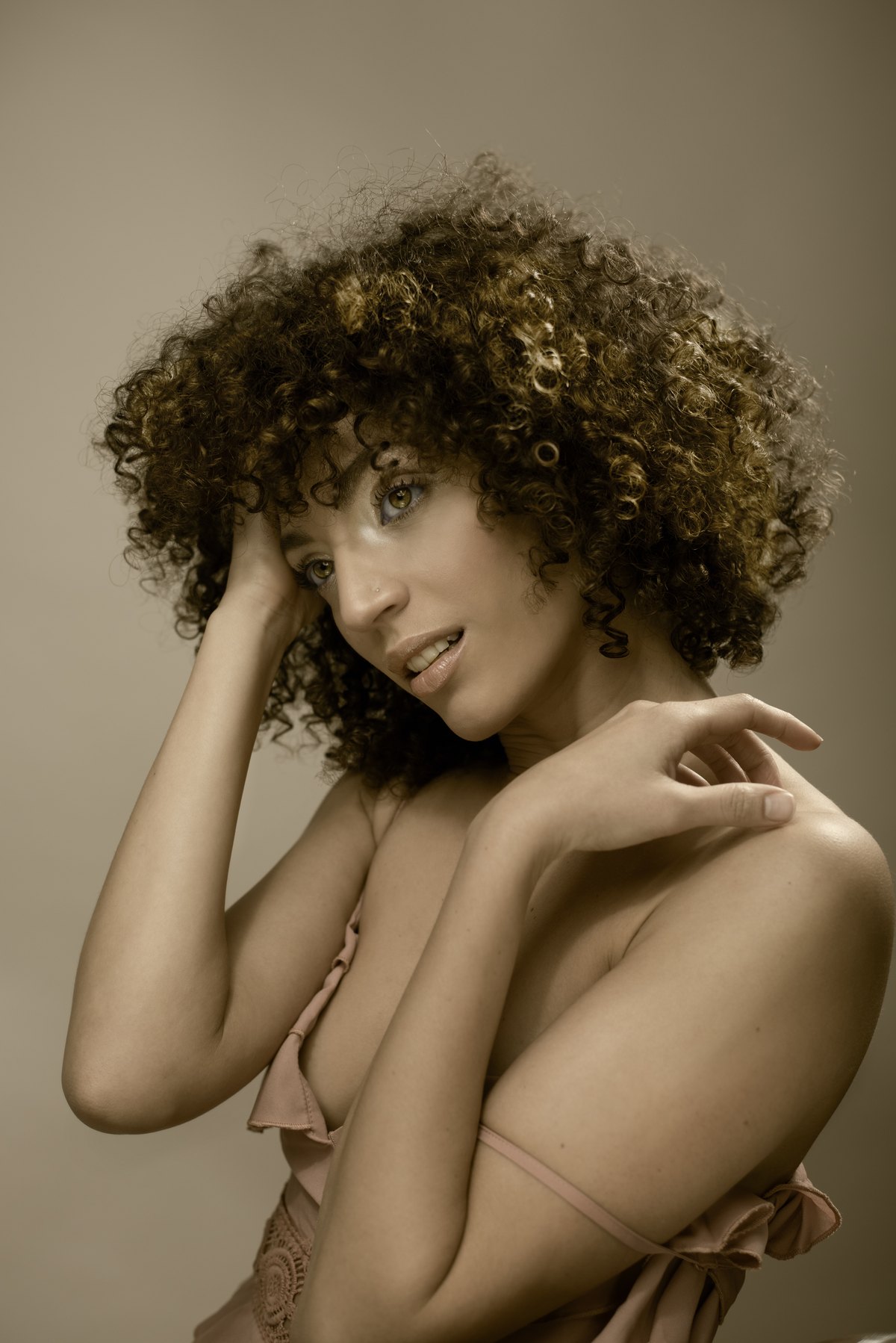 Frau mit voluminösen Locken im Schulterblick, warmes Licht