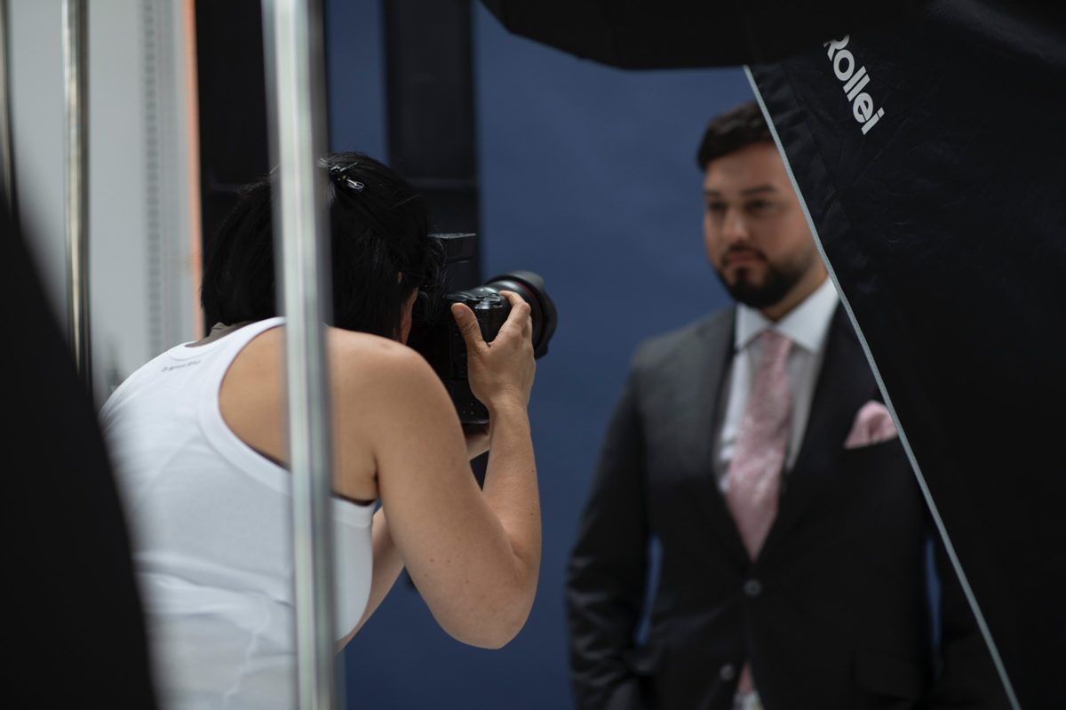 Fotografin beim Business-Porträtshooting eines Mannes im Anzug vor blauem Hintergrund