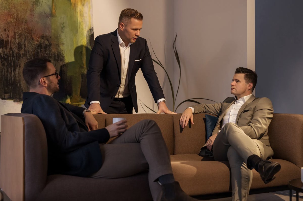 Drei Männer im Gespräch in einer hellen Lounge