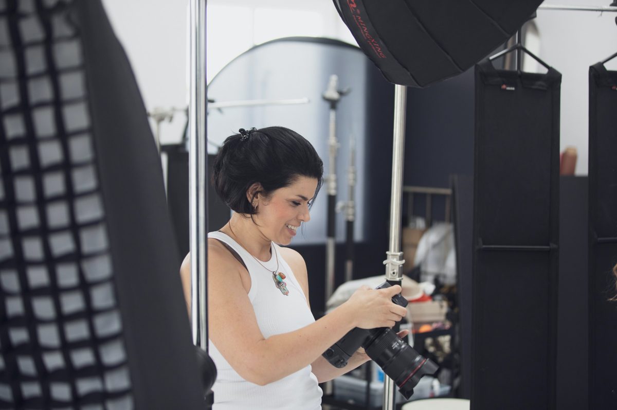 Fotografin mit Kamera am Set zwischen Lichtformern und Stativen
