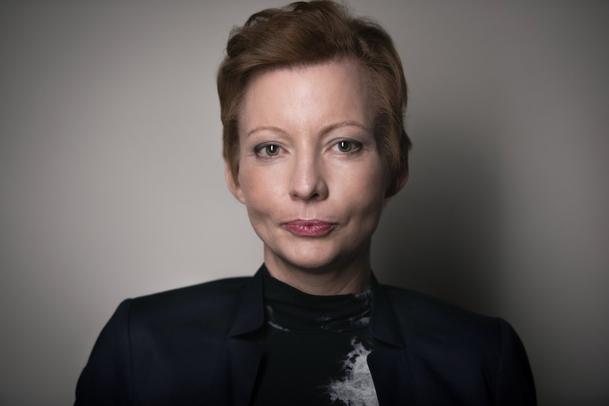 Portrait einer Frau im dunklen Blazer vor grauem Hintergrund