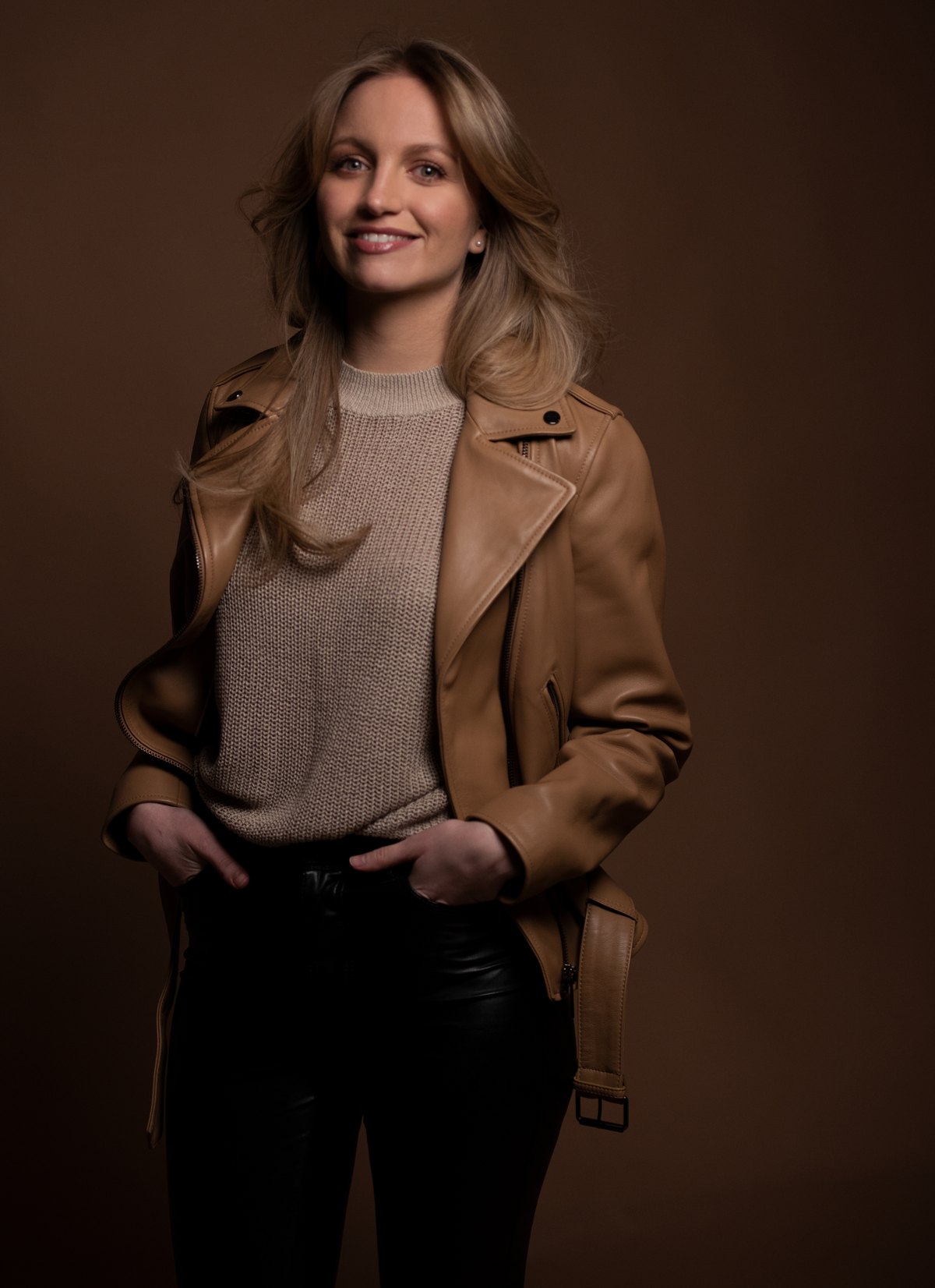 Frau in camelfarbener Lederjacke vor dunklem Hintergrund