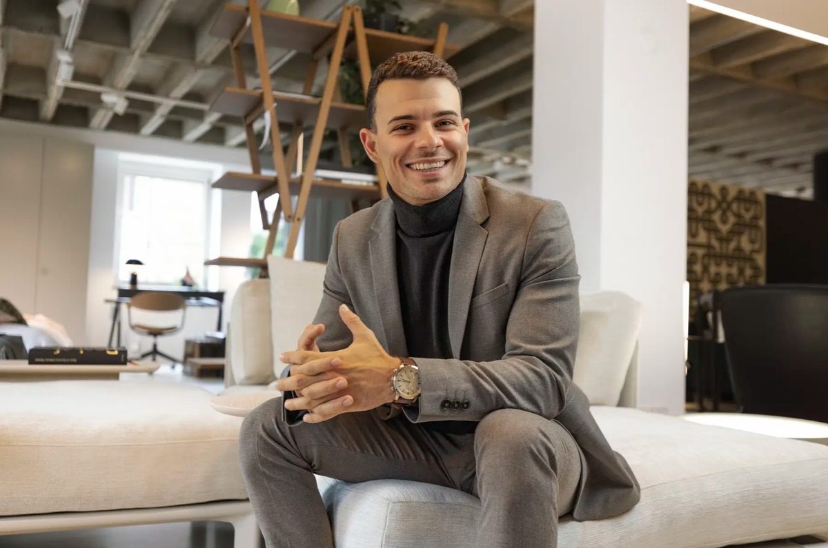 Businessportrait eines lachenden Mannes im grauen Anzug auf einem Sofa in einem hellen Loft