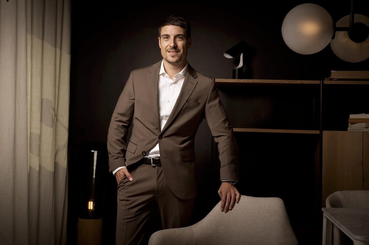 Stehendes Businessportrait eines Mannes im braunen Anzug in dunklem, modernem Interieur