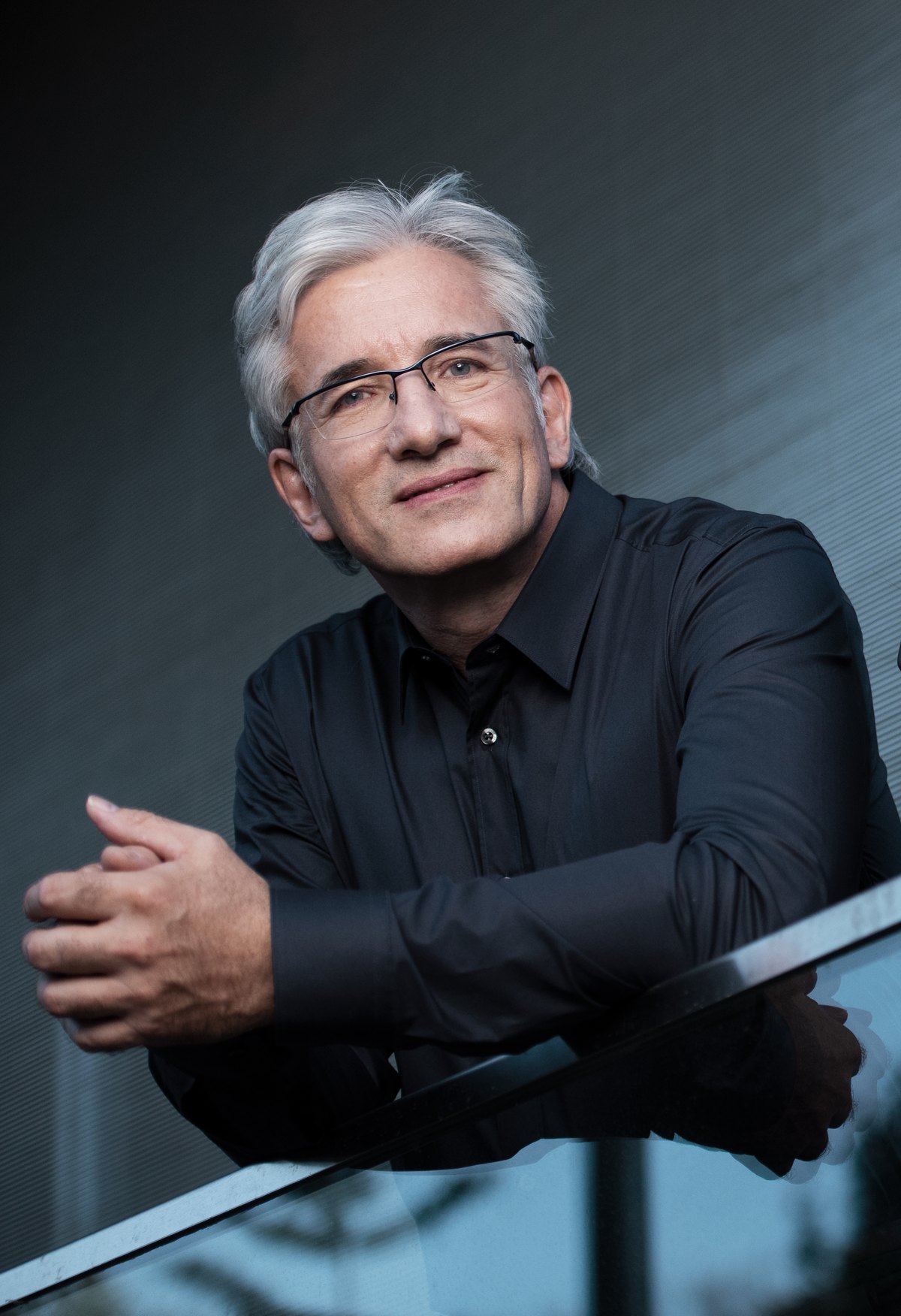 Mann mit Brille lehnt an einem Geländer in blauer Lichtstimmung