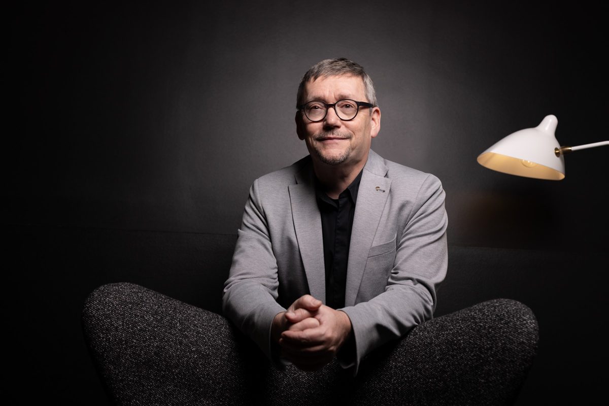 Businessportrait eines Mannes mit Brille im grauen Sakko vor dunklem Studiohintergrund