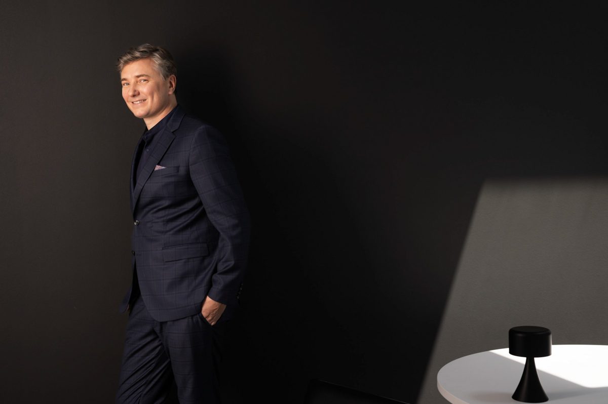 Businessportrait eines Mannes im dunkelblauen Anzug an einer dunklen Wand mit hellem Lichtfeld