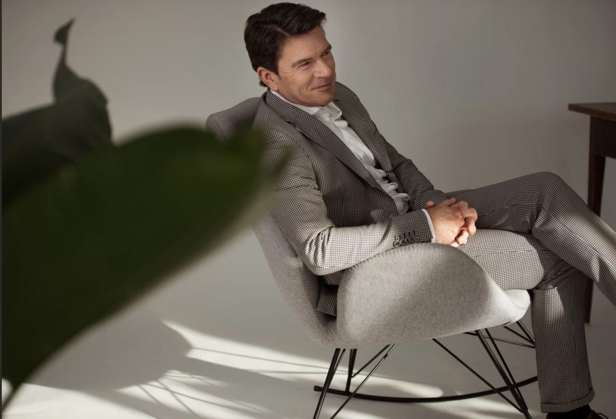 Businessportrait eines Mannes im hellgrauen Anzug in einem Designsessel vor heller Wand