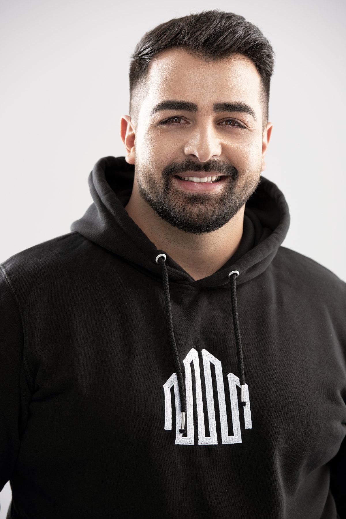 Lachender Mitarbeiter im schwarzen Hoodie mit Firmenlogo