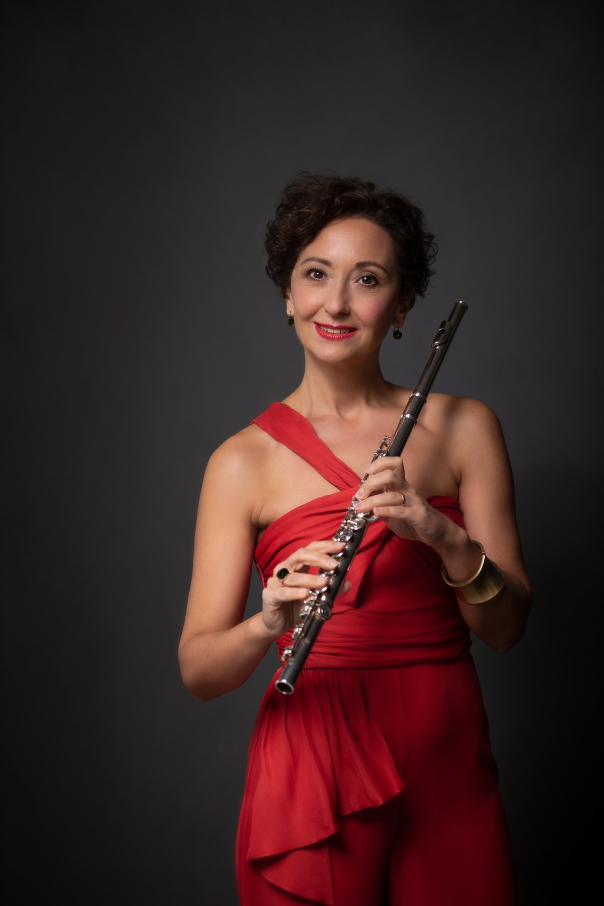 Musikerin im roten Kleid mit Querflöte vor dunklem Hintergrund