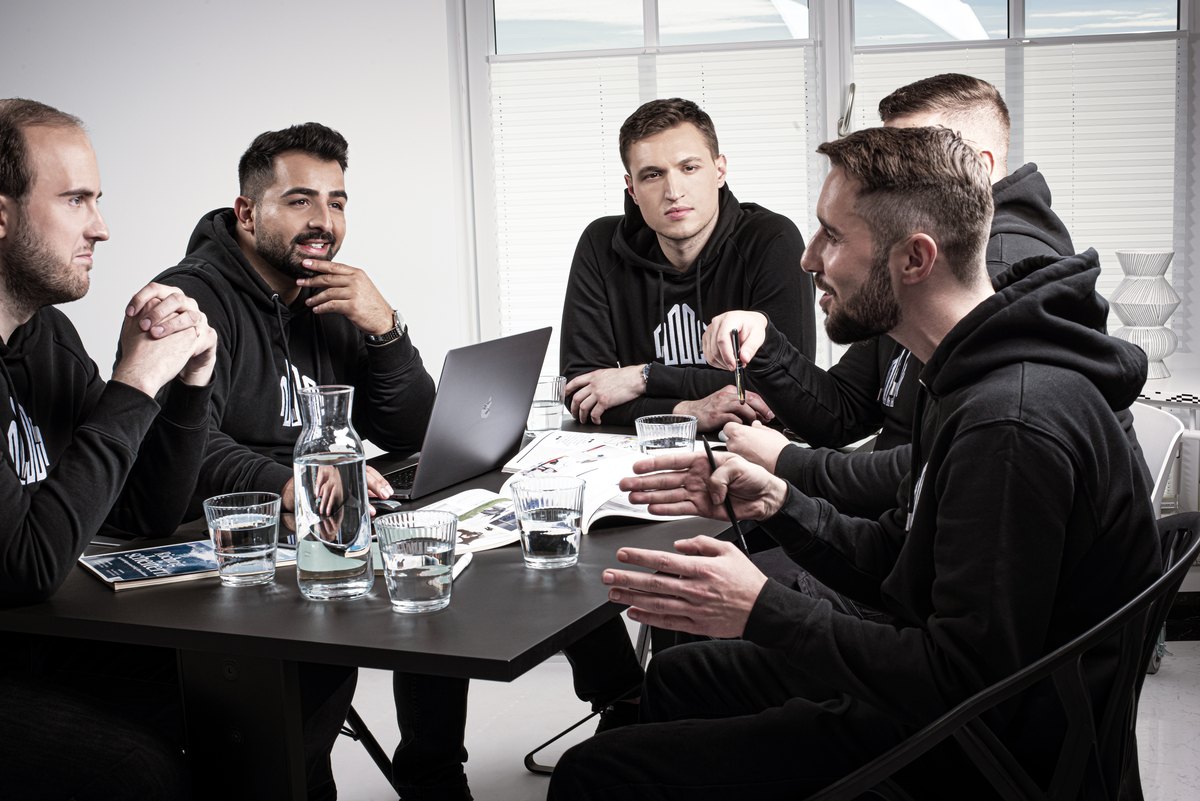 Team in dunkler Arbeitskleidung bei einer Besprechung am Laptop
