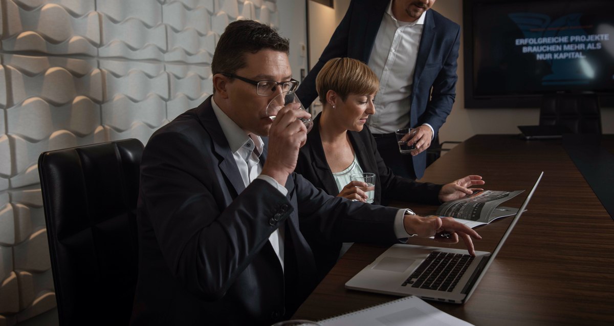 Team am Laptop bei einer Präsentation in dunklem Raum
