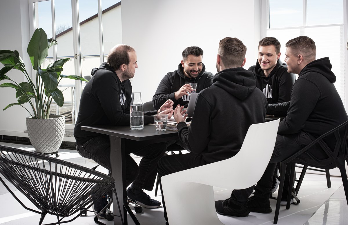 Team am Besprechungstisch in hellem Büro mit Pflanzen