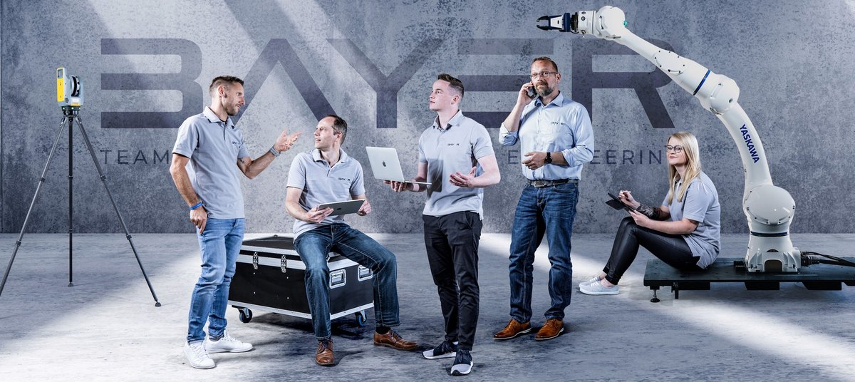 Fünfköpfiges Team gruppiert um Industrieroboterarm und Messtechnik