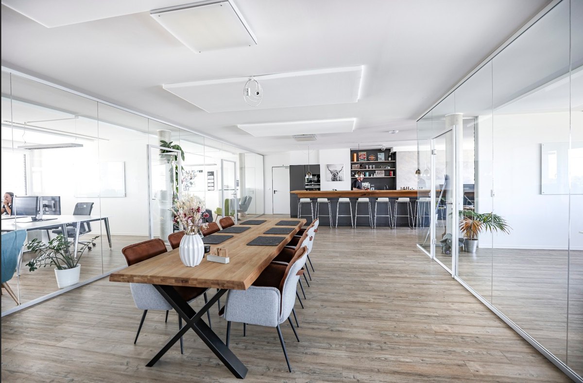 Lichtdurchflutetes Großraumbüro mit Holztafel und Glaswänden