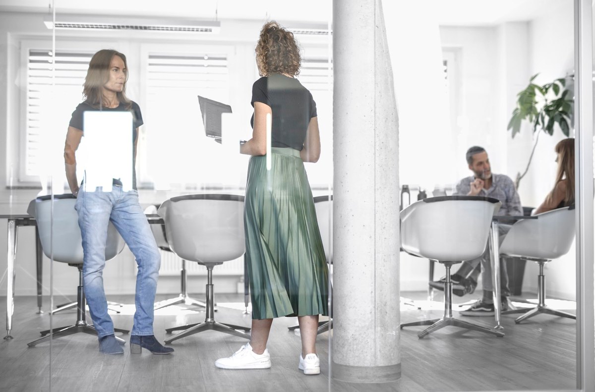 Personen im Gespräch vor Glaswand im modernen Büro