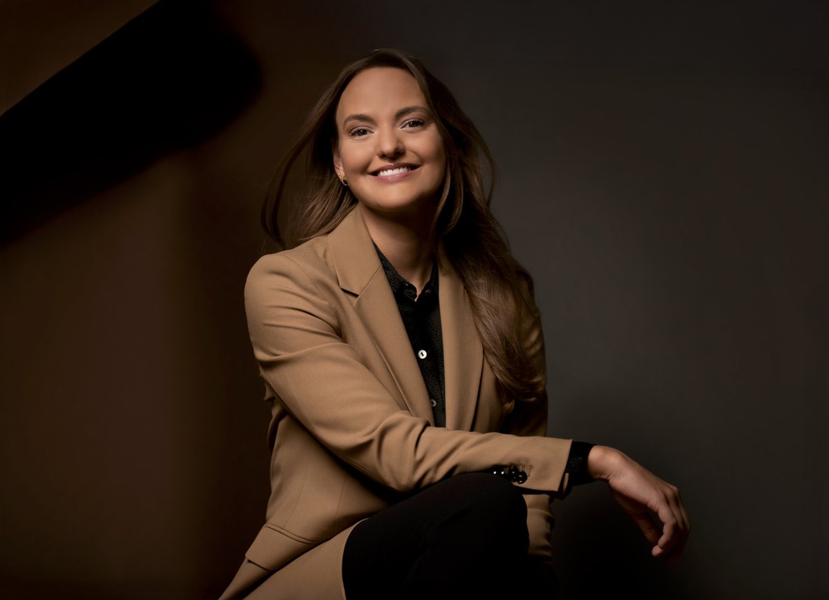 Frau im camelfarbenen Blazer sitzt im Low-Key-Licht