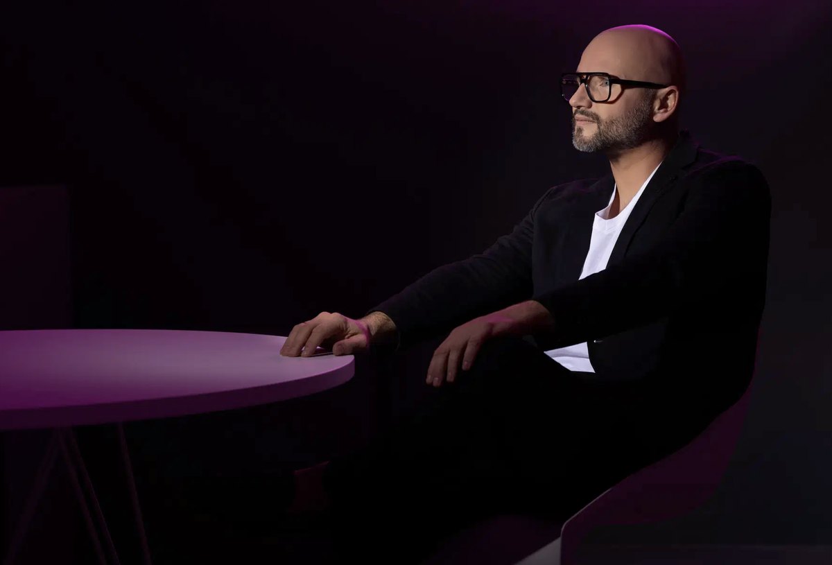 Mann im Anzug am Tisch in violetter Lichtstimmung